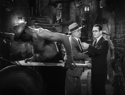 Harold Lloyd standing besides a man sharpening a sword in his darkest sound film.