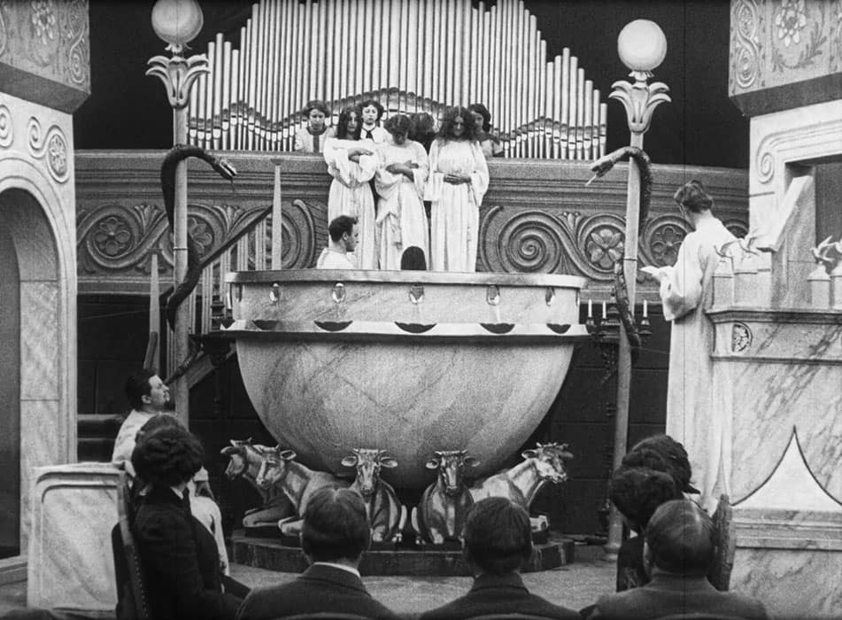 A man is baptizing a woman in a depiction, from A Victim of the Mormons (1911), in a replicated Salt Lake Temple.